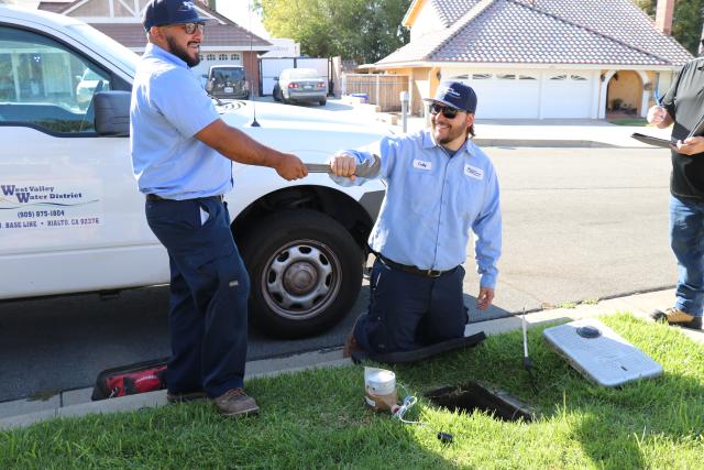 Meter staff working together to replace meter at customer home